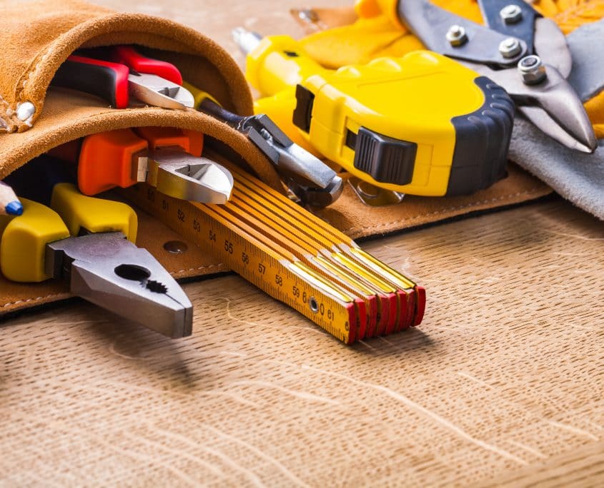construction tools in toobelt very close up on wooden board